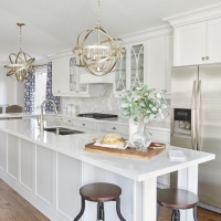 Interior-Kitchen-white-cabinetry-and-walls-with-stainless-steel-appliances-and-wooden-stools-herrigbone-backsplash-marble-white-quartz-countertops-and-hardwood-flooring-min