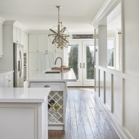 Kitchen-interior-with-white-cabinetry-and-quartz-countertop-with-hardwood-flooring-and-gold-pendant-lighting-and-wine-rack-min