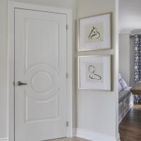 Light-hardwood-flooring-with-decorative-white-door-and-crown-moulding-and-gallery-wall-min