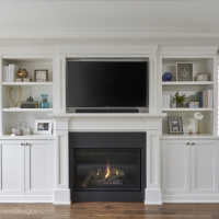 Living-room-with-white-custom-cabinetry-with-fireplace-and-television-and-dark-hardwood-flooring-built-in-cabinetry-with-custom-bench-seating-under-window-min