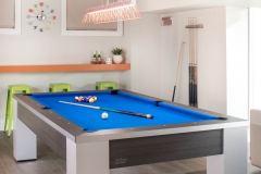 Basement-game-area-with-blue-pool-table-and-green-and-orange-bar-seating