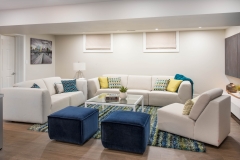 Basement-living-room-with-white-and-blue-seating-and-blue-and-green-rug