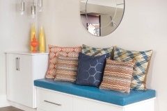 Basement-seating-with-white-custom-cabinetry-and-blue-and-orange-pillows
