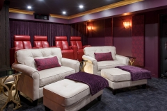 Basement-theatre-with-purple-walls-and-large-white-chairs-and-red-movie-theatre-chairs